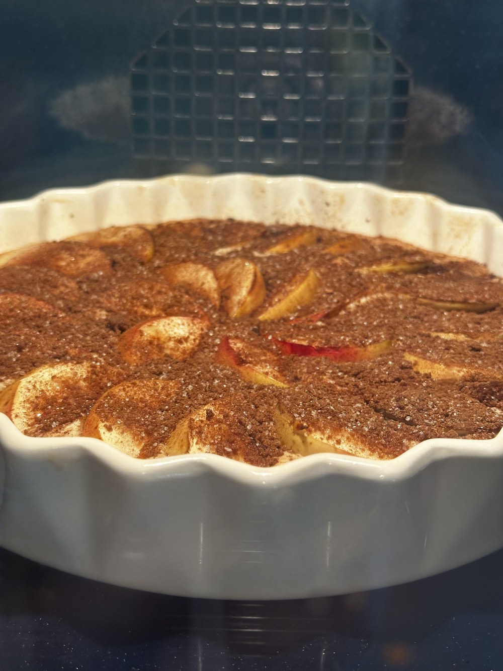 Den nybagte æblekage i den hvide tærteform med kanel og brun farin ovenpå