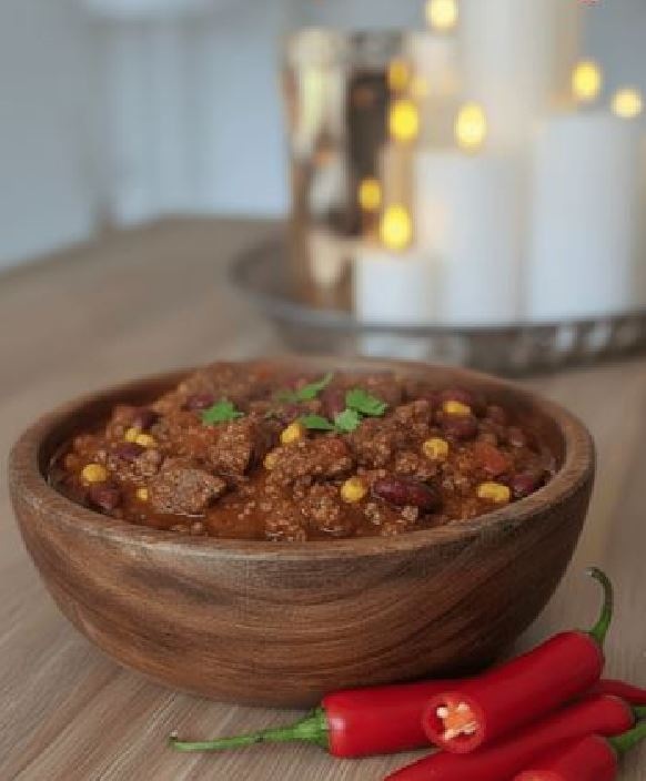 Chili con carne i træskål med chili ved siden af