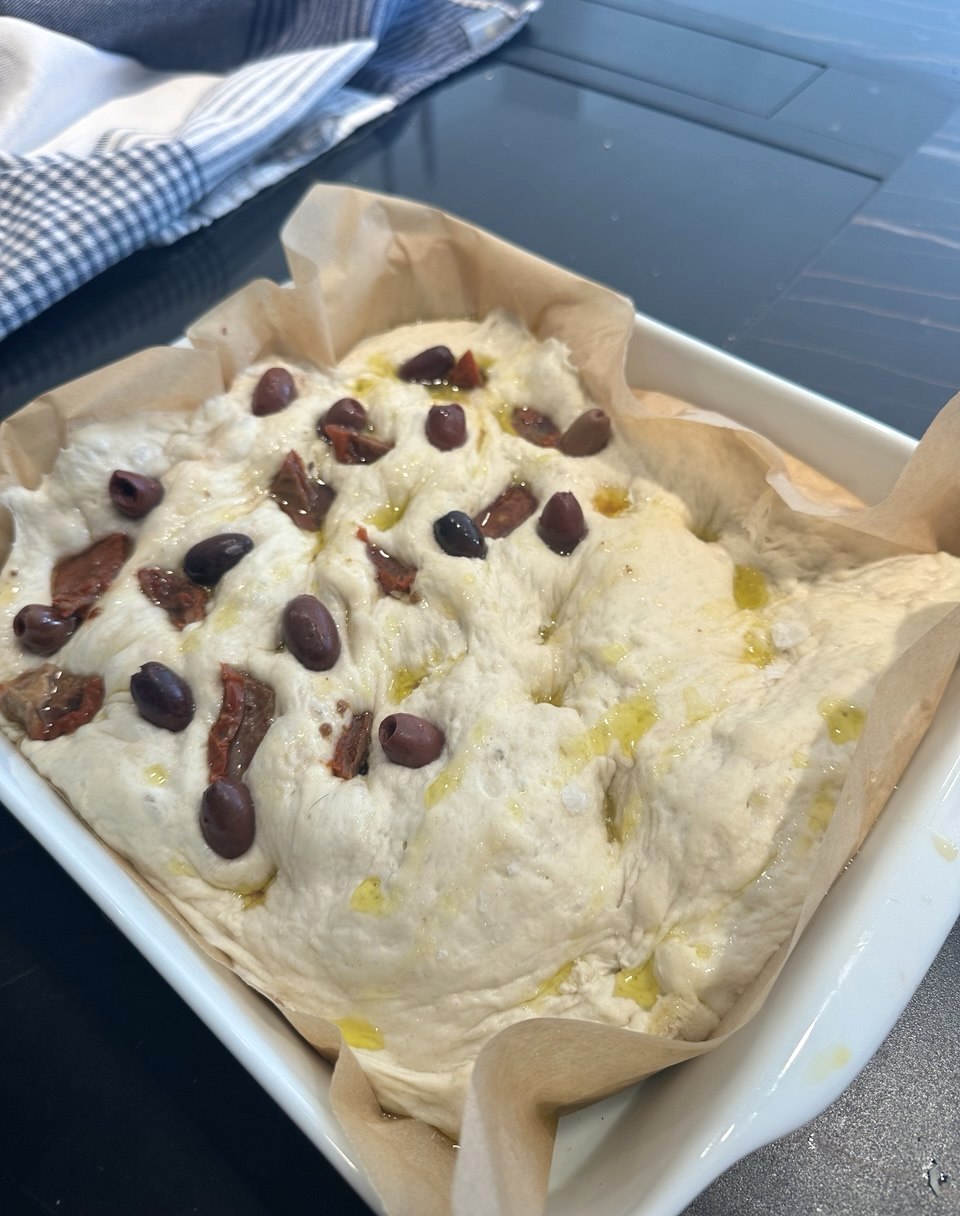 Focaccia pyntet med oliven og soltørrede tomater før bagning