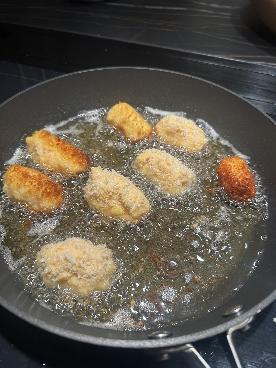 Kartoffelkroketter i pankorasp, der steges gyldne i olie på en pande